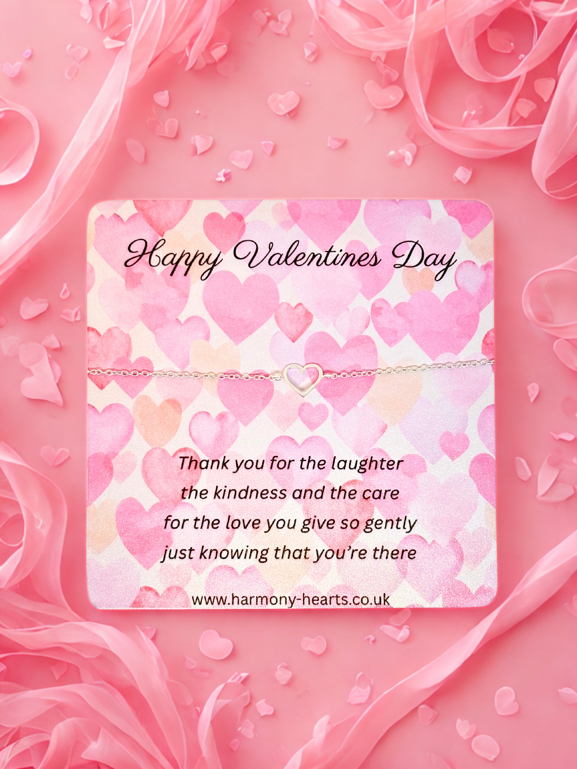 Valentine's Day card with hearts and a message on a pink background with a silver heart bracelet