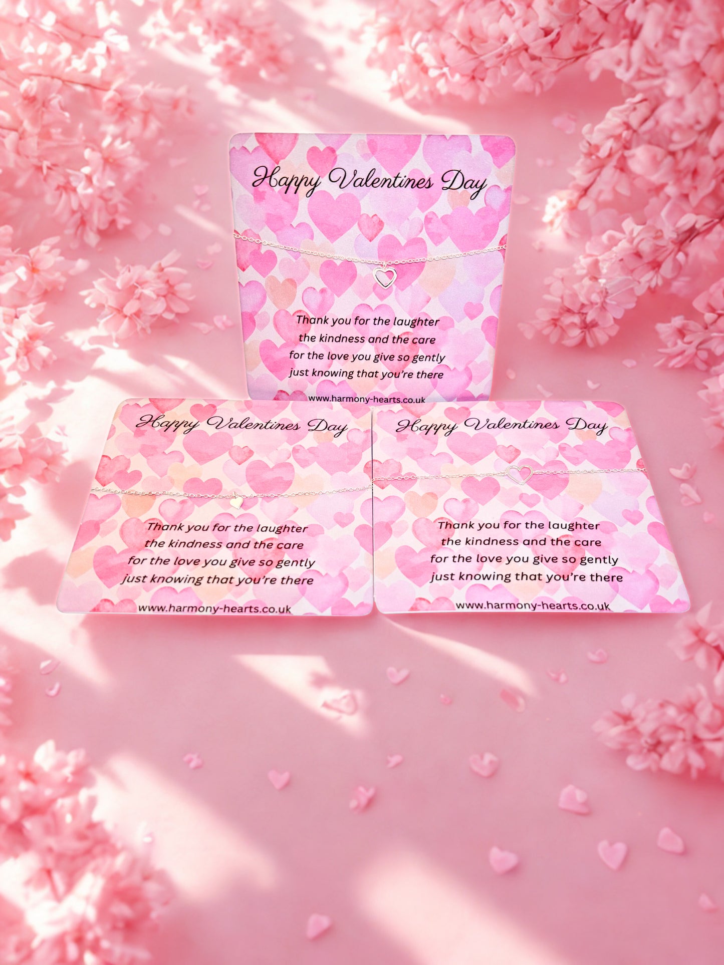 Valentine's Day card with pink hearts on a pink floral background with silver heart bracelets