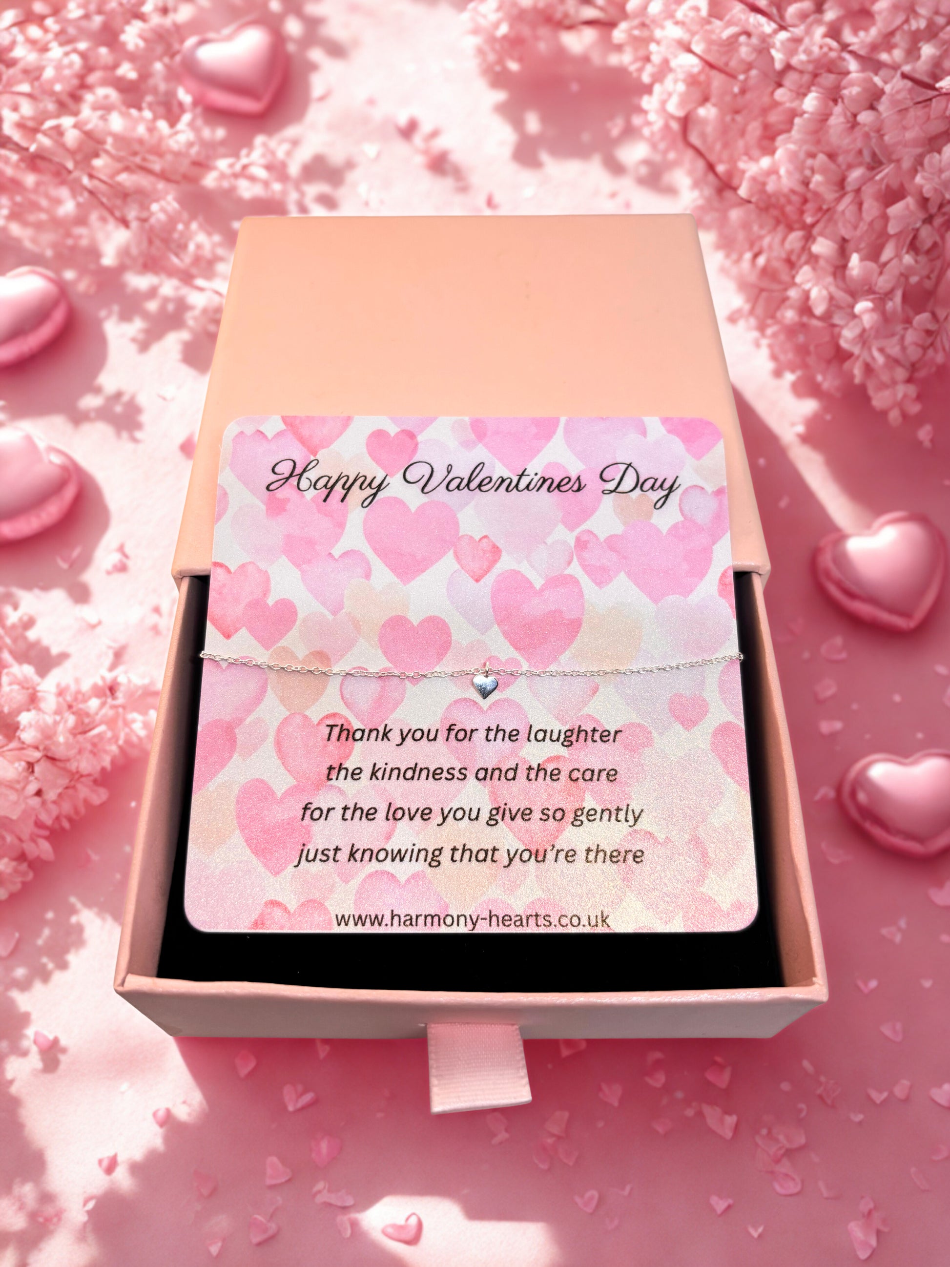 Valentine's Day card iwith a silver heart bracelet in a pink box with heart-themed design on a pink background