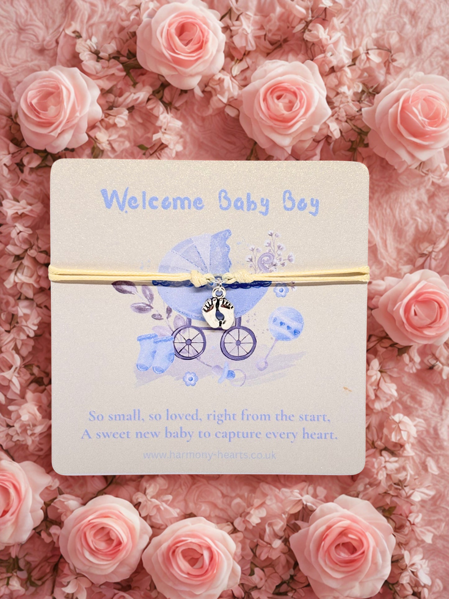 Charm bracelet on a baby shower card with stroller charm on a pink floral background