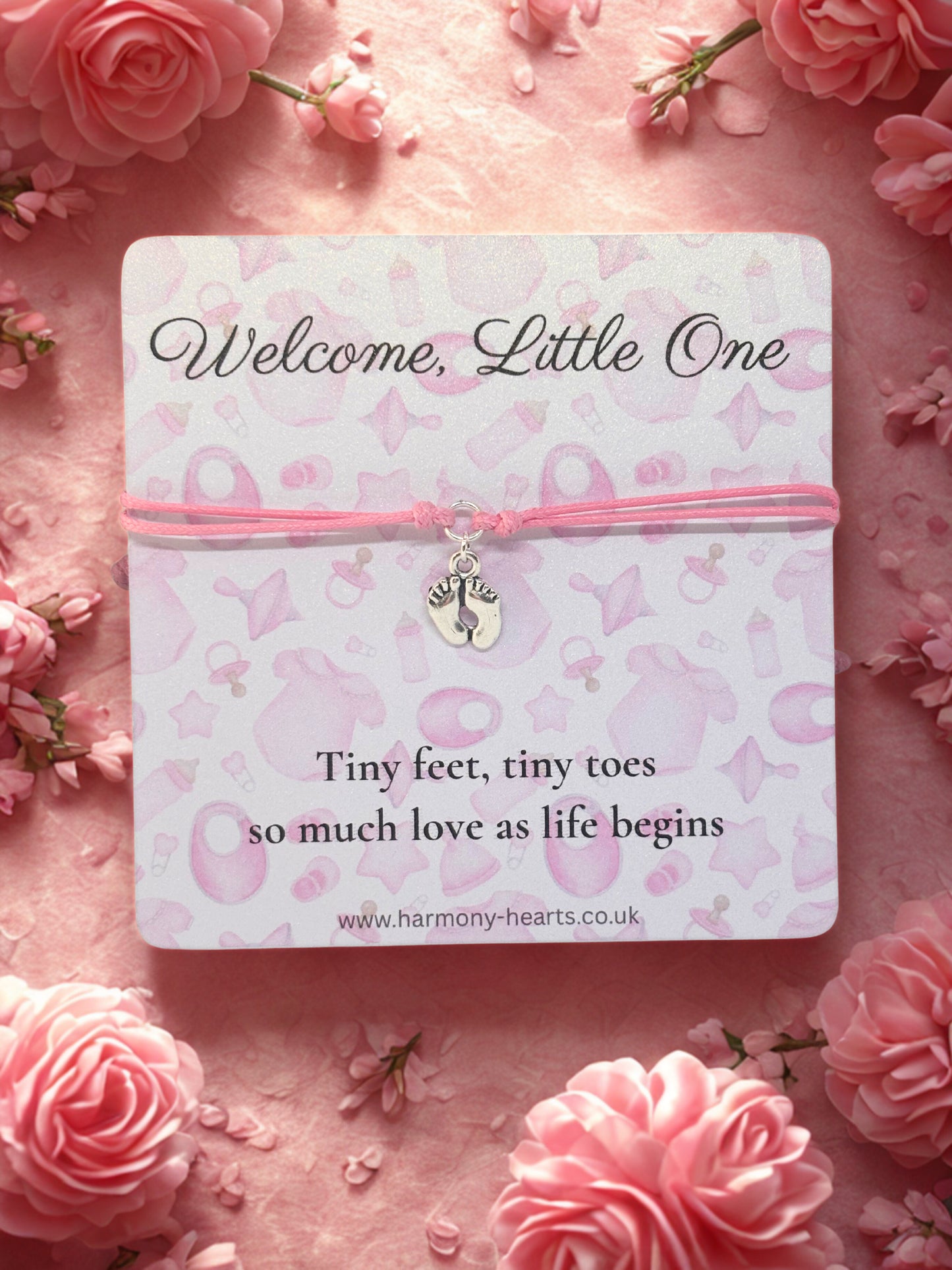 Baby shower gift with pink cord and charm on a card with floral background