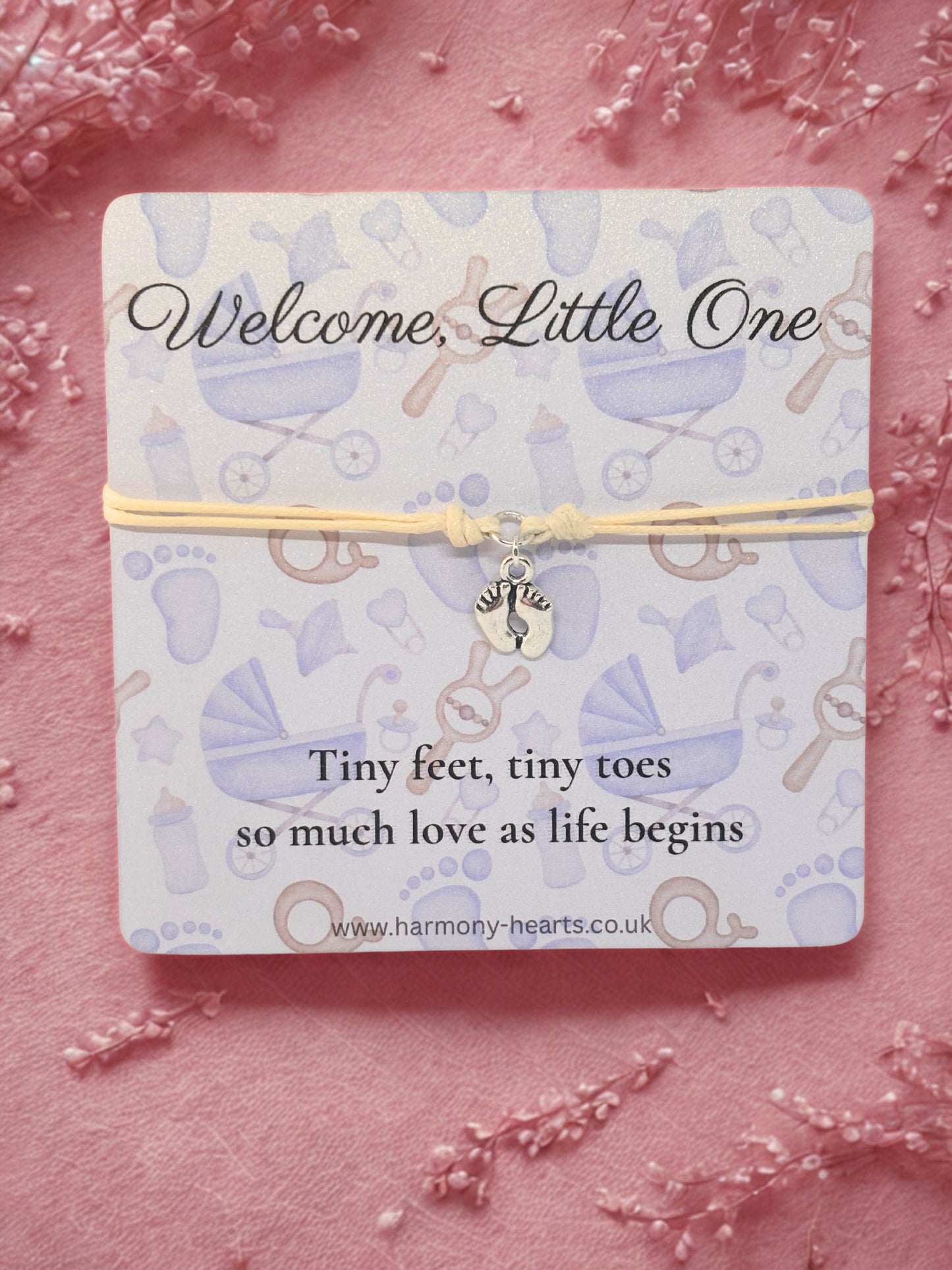 Baby-themed bracelet on a matching card with decorative elements on a pink background