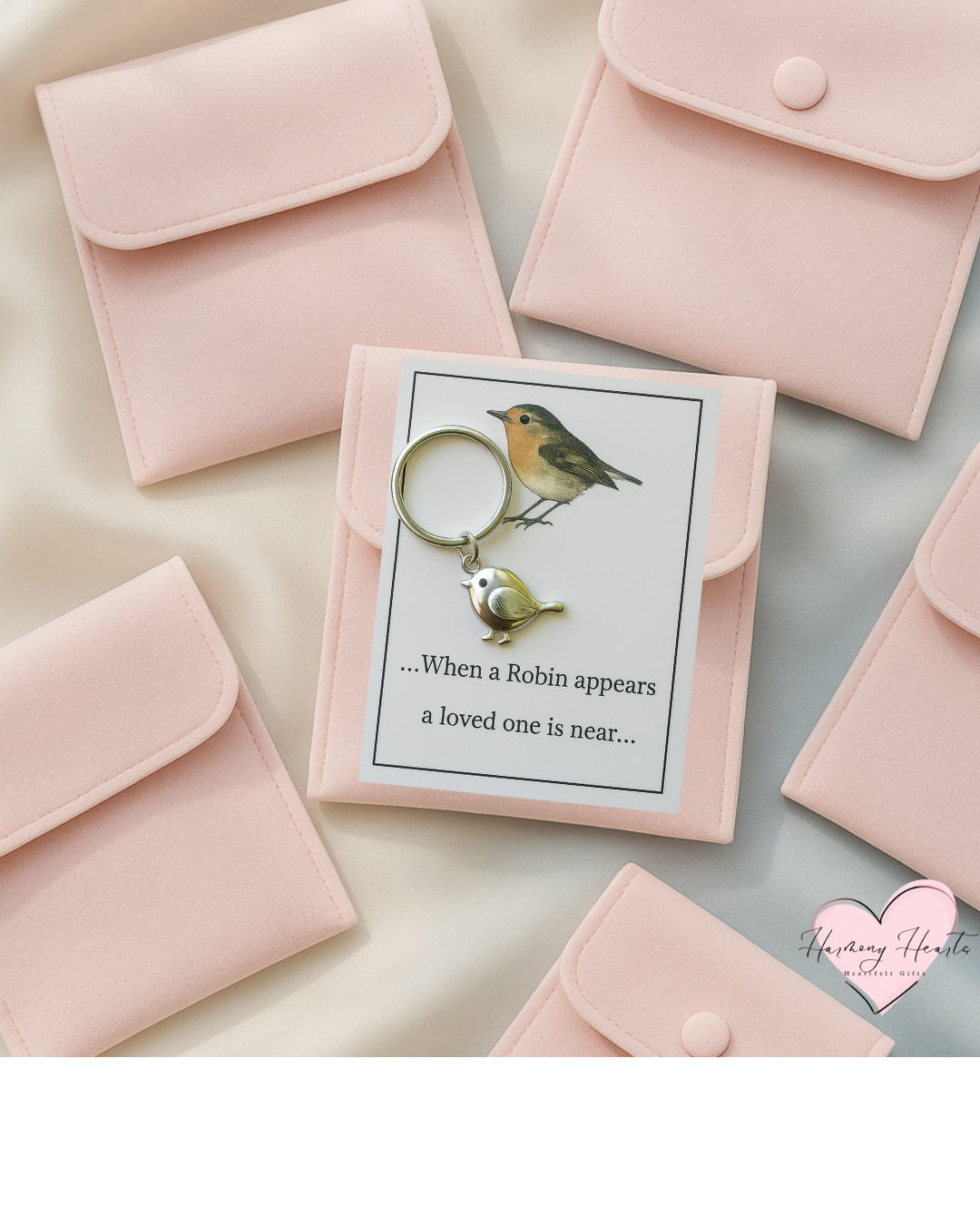 A silver robin keyring attached to a card with the message 'When a Robin appears, a loved one is near.' Presented alongside pink velvet pouches.