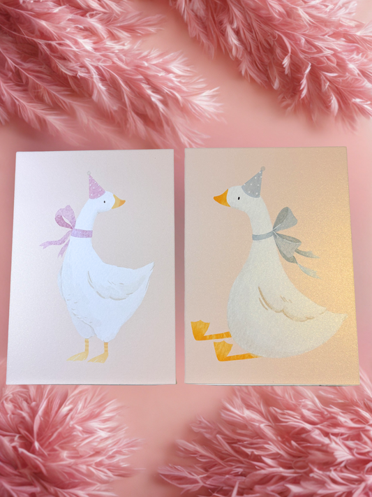 Two prints with illustrated ducks on a pink fluffy surface