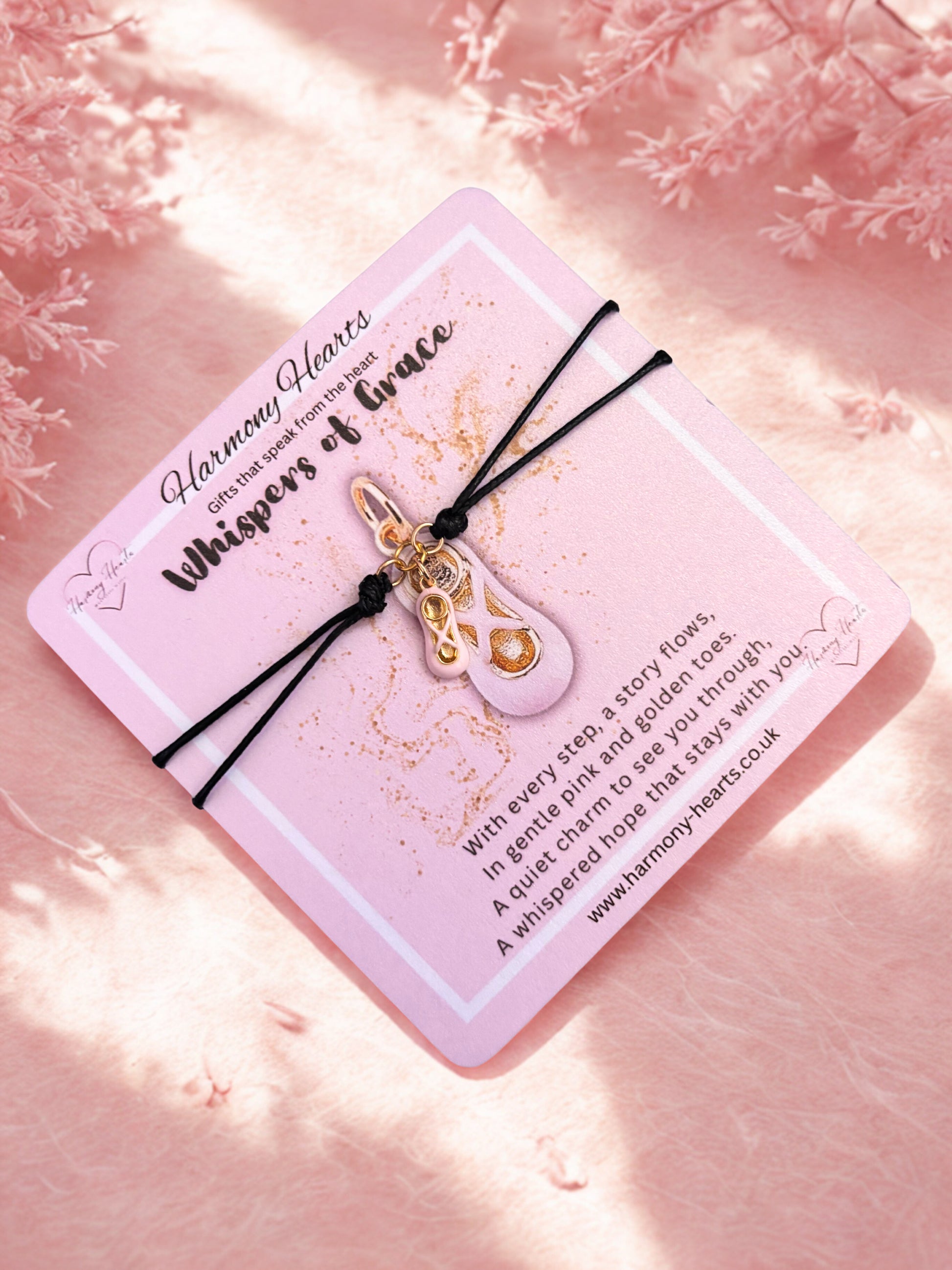 Bracelet with gold and pink ballet shoe charm on a pink card with text, against a soft pink background