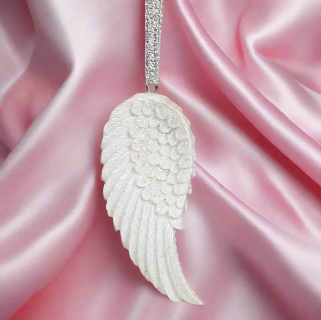 White angel wing pendant on a pink satin background