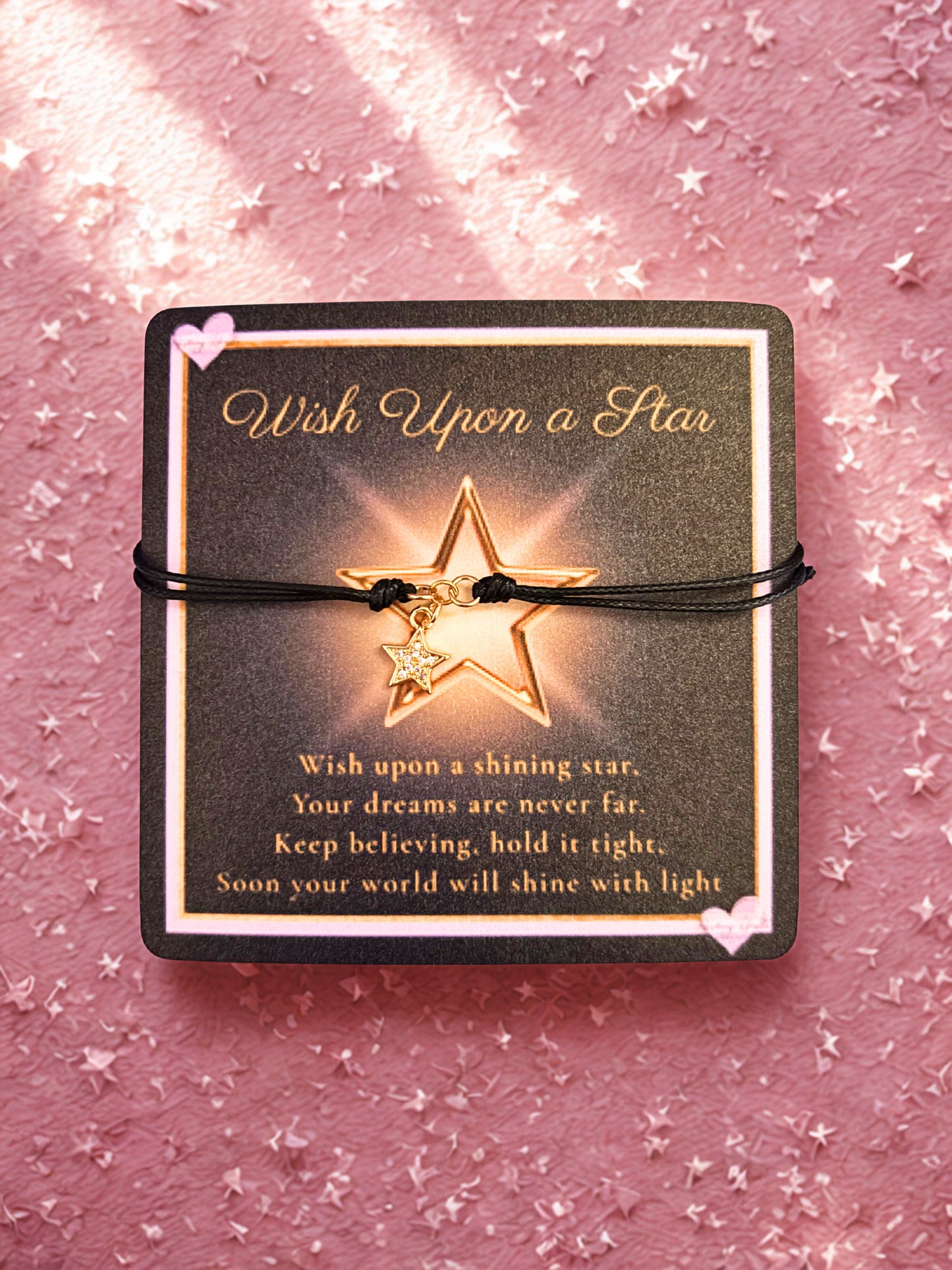 Gold star bracelet on a matching card with 'Wish Upon a Star' text against a pink glittery background.