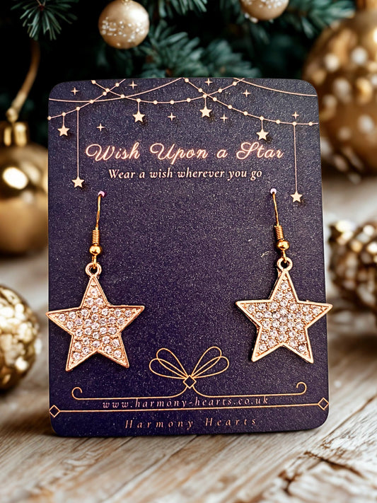 Star-shaped earrings on a card with Christmas decorations in the background