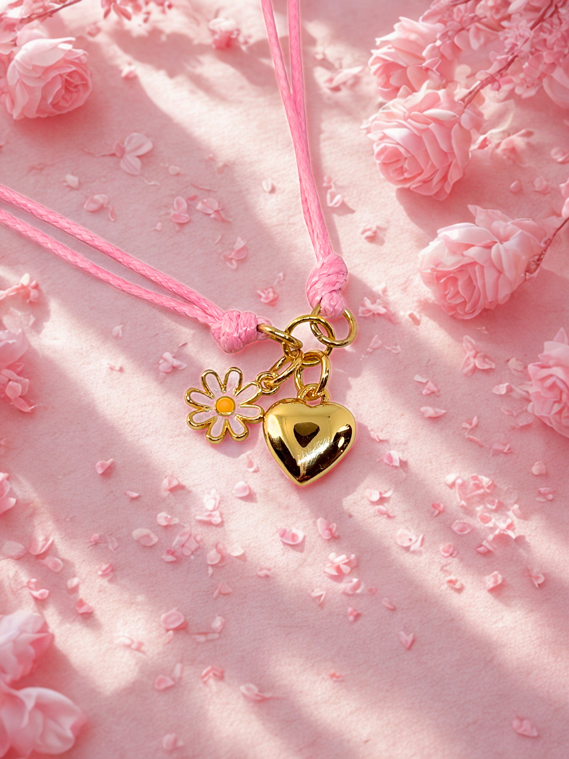 Gold heart and flower charm bracelet on a pink floral background