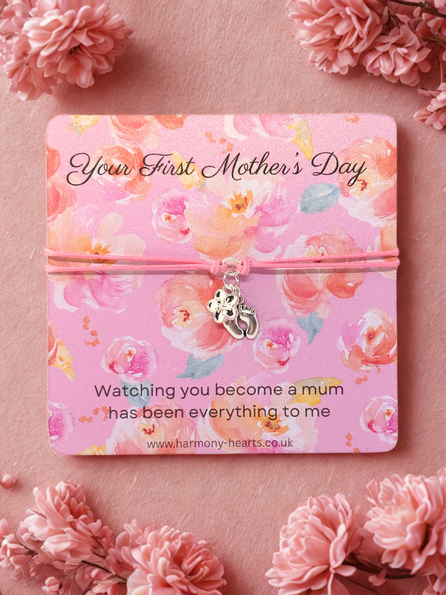 Charm bracelet on Floral-themed card with 'Your First Mother's Day' message on a pink background with flowers.