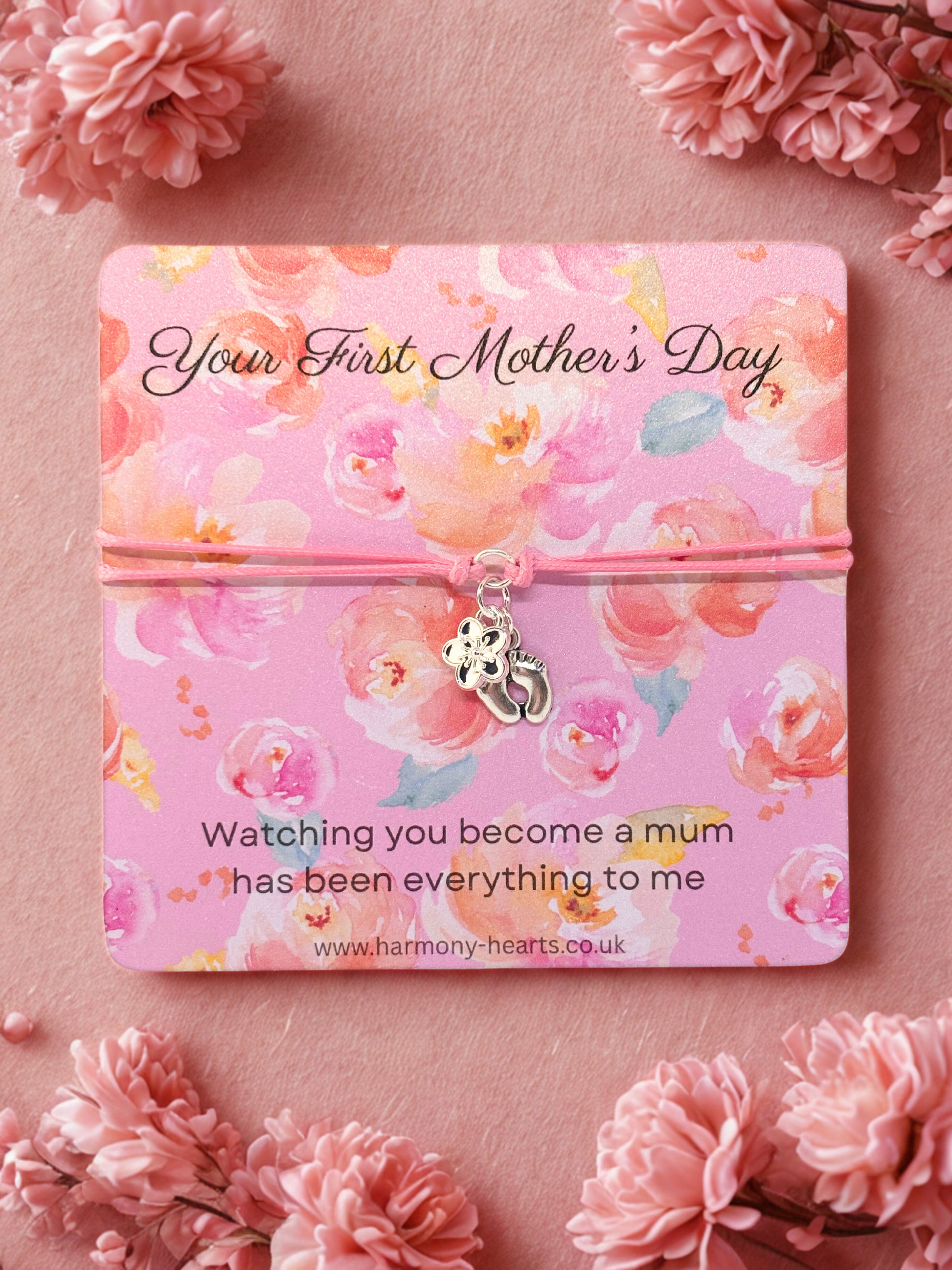 Charm bracelet on Floral-themed card with 'Your First Mother's Day' message on a pink background with flowers.