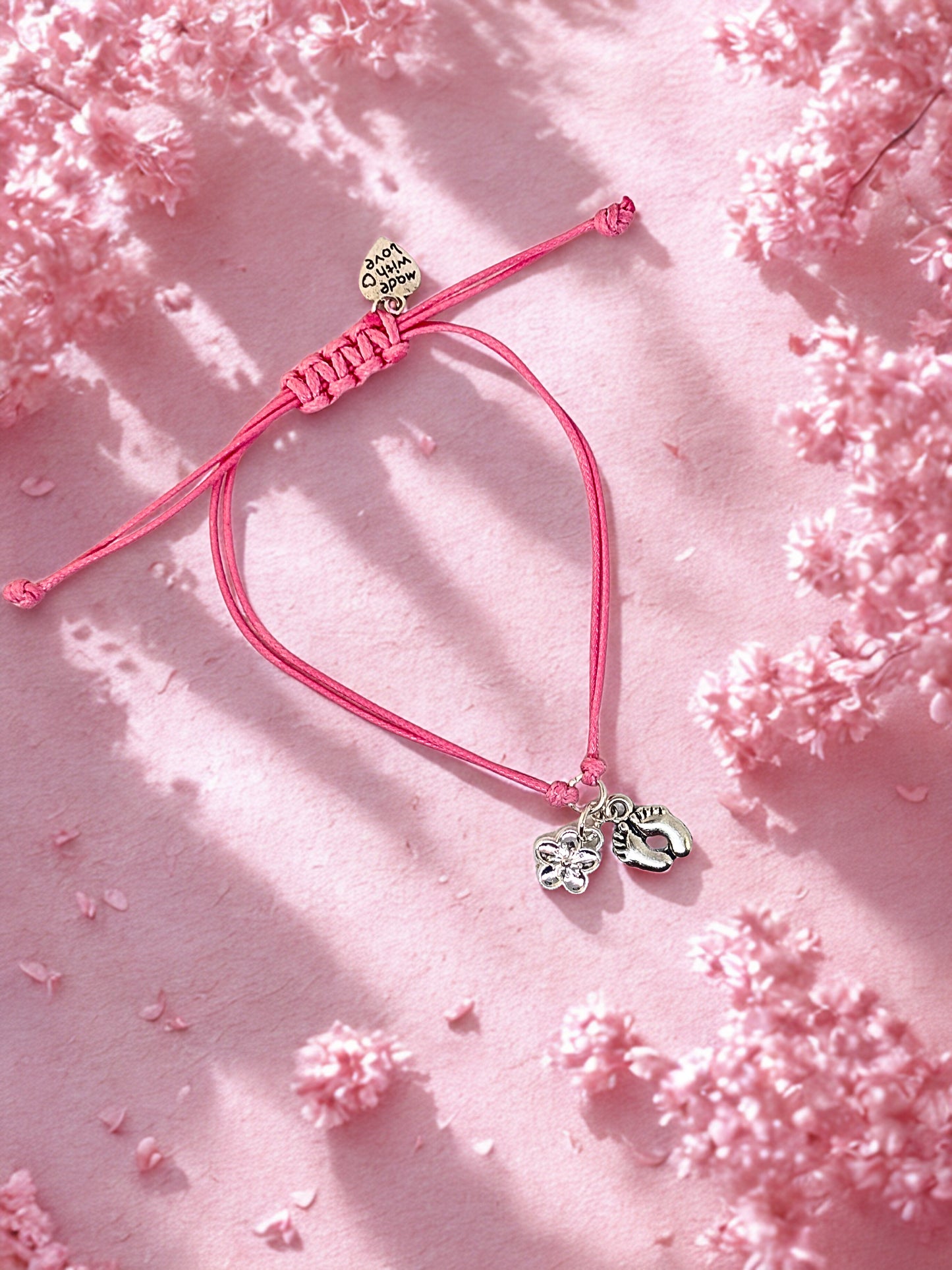 Pink bracelet with silver charms on a pink floral background